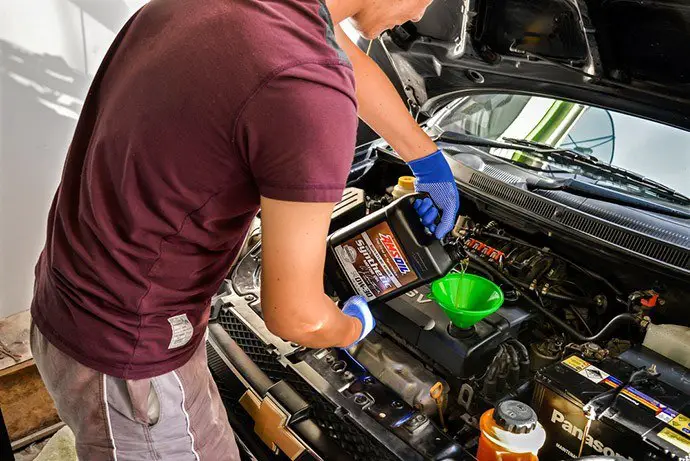 The man pours the oil into the engine
